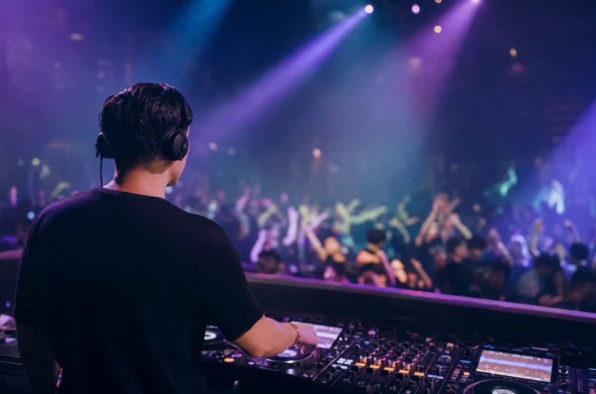 DJ reading the crowd from the booth at a busy club dance floor