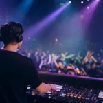DJ reading the crowd from the booth at a busy club dance floor