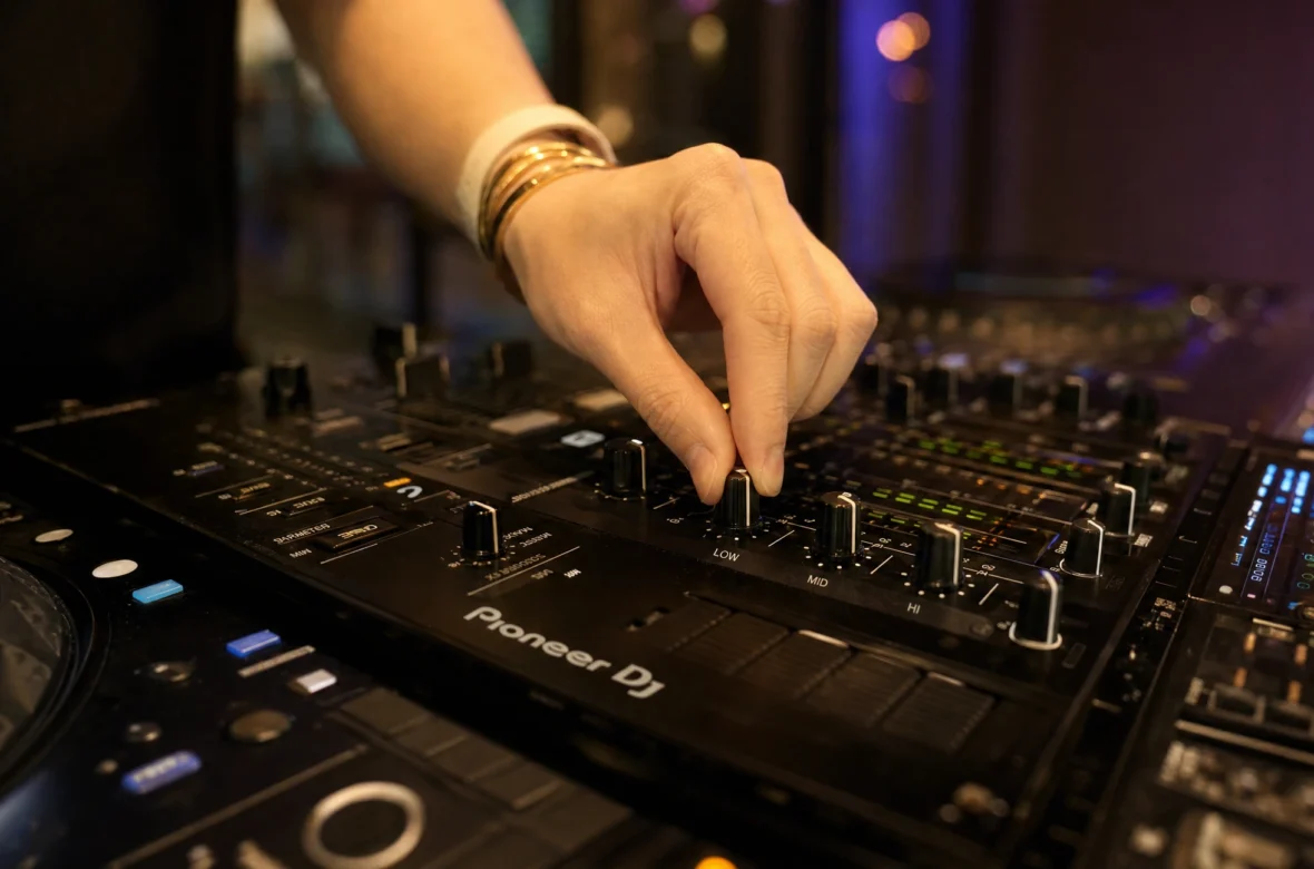 DJ adjusting low mid high EQ knobs on a mixer while mixing
