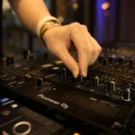 DJ adjusting low mid high EQ knobs on a mixer while mixing