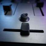 Close-up of a DJ mixer crossfader and curve knob in a dark DJ booth