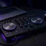 Compact DJ controller connected to a laptop with headphones beside it in a dark studio