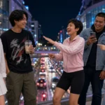 Five young Thai friends with shopping bags on a skywalk between malls in Siam at night.
