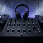 Club mixer and two media players in a dark, hazy industrial techno DJ booth with strobe beams